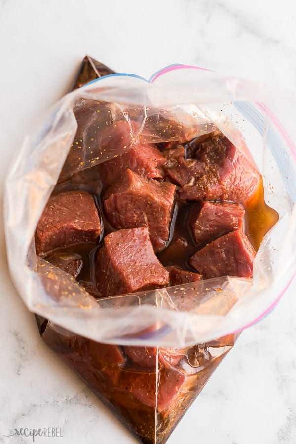 These Steak Kabobs are made with an easy kabob marinade and loaded with tender steak, bell peppers and red onions. Easy to make and easy to prep ahead for summer entertaining! #steak #kabobs #grilled #grilling #beef steak cubes in marinade
