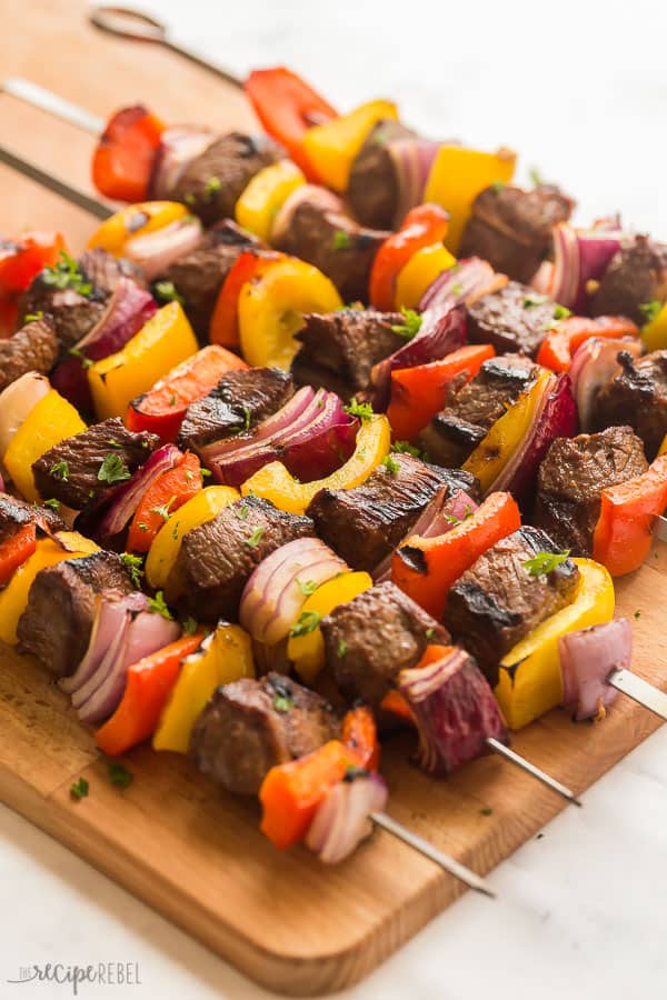 These Steak Kabobs are made with an easy kabob marinade and loaded with tender steak, bell peppers and red onions. Easy to make and easy to prep ahead for summer entertaining! #steak #kabobs #grilled #grilling #beef steak kabobs up close on wood