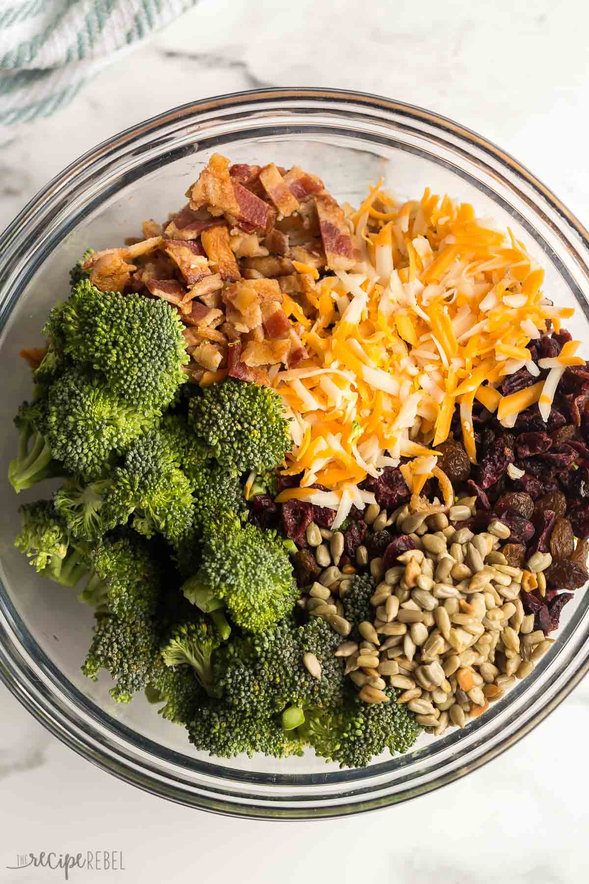 overhead image of ingredients needed for broccoli salad in a glass bowl.