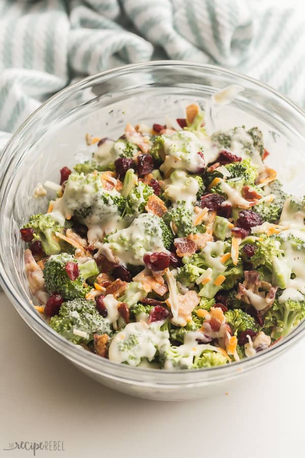 broccoli salad in glass bowl with cranberries cheese and bacon