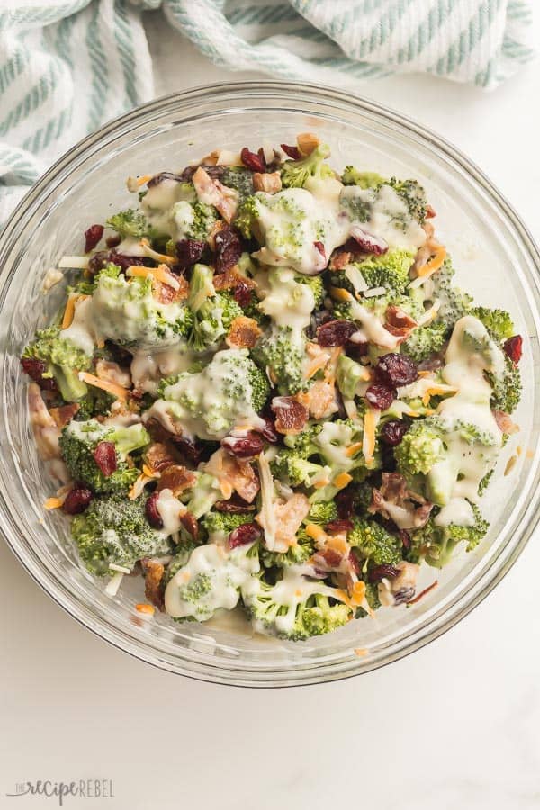 broccoli salad with dressing overhead in large glass bowl on white background