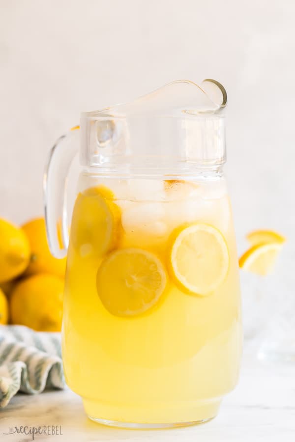 This homemade Lemonade recipe is so easy to make and perfect for summer! Also includes instructions for blueberry lemonade and strawberry lemonade, plus other variations and uses. #lemon #lemonade #drink #recipe #strawberry #blueberry homemade lemonade recipe in large glass pitcher with lemon slices