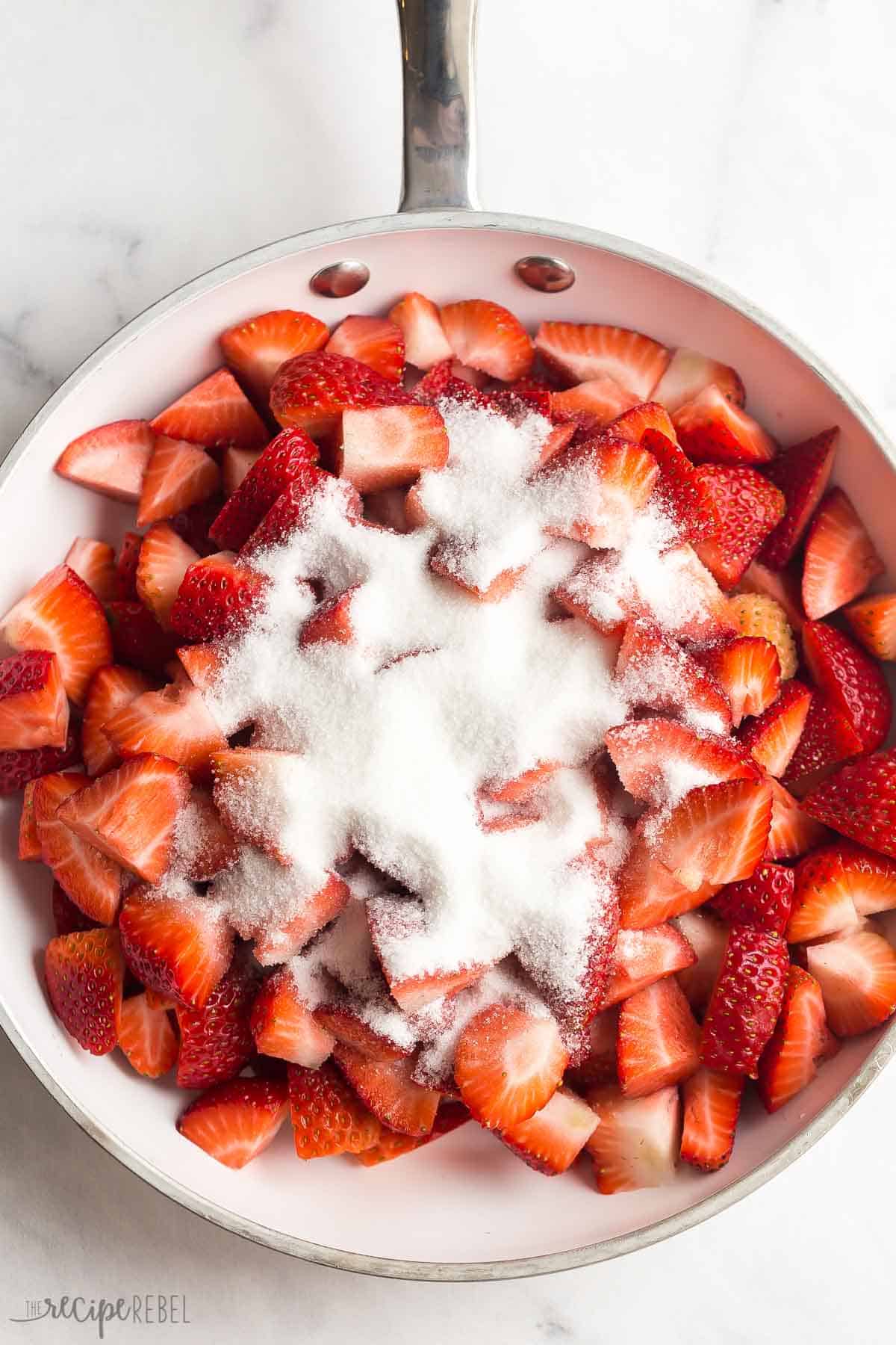 This easy Strawberry Sauce is made with fresh or frozen strawberries and perfect on waffles, pancakes, or ice cream! #strawberry #strawberries #dessert #recipe | strawberry recipes | strawberry desserts | easy dessert recipes | fresh strawberry sauce fresh strawberries chopped in a white skillet with sugar.