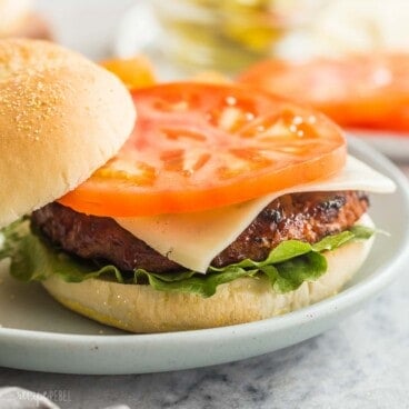 square image of a grilled turkey burger on a bun with tomato lettuce and cheese.