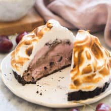 baked alaska tart on white plate cut in half to reveal black jack cherry yogurt