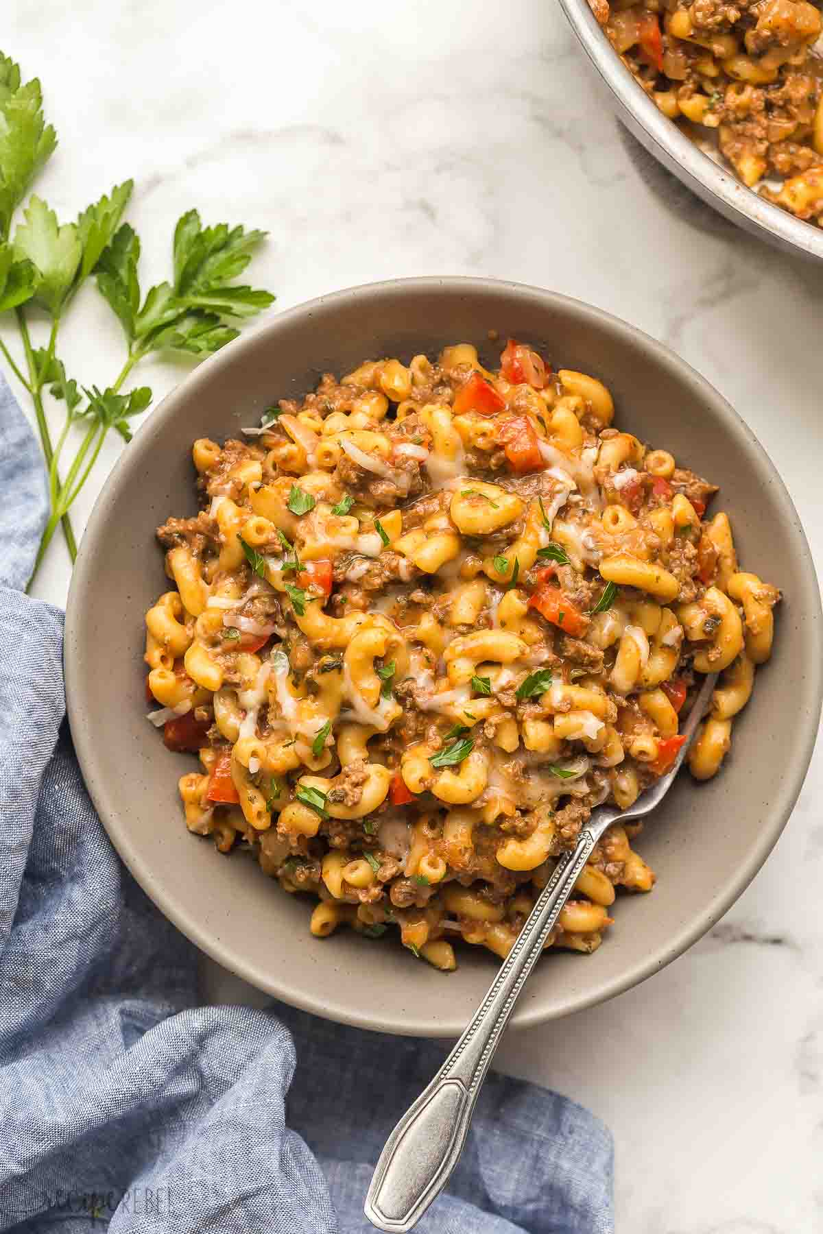 grey bowl of hamburger helper recipe with fork stuck in.