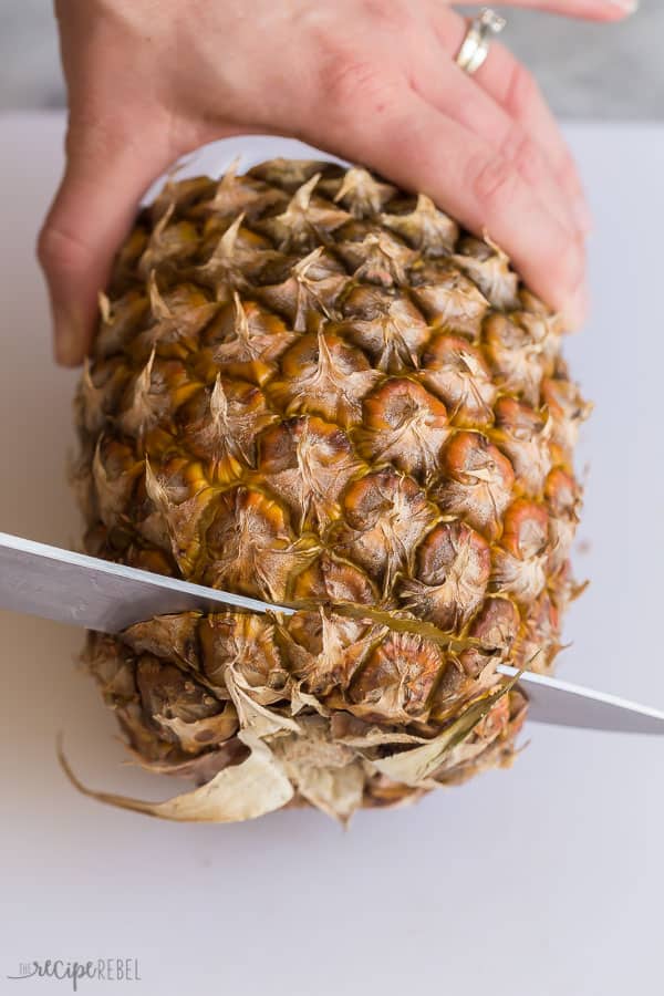 cut the bottom off the pineapple with a sharp knife on a white cutting board