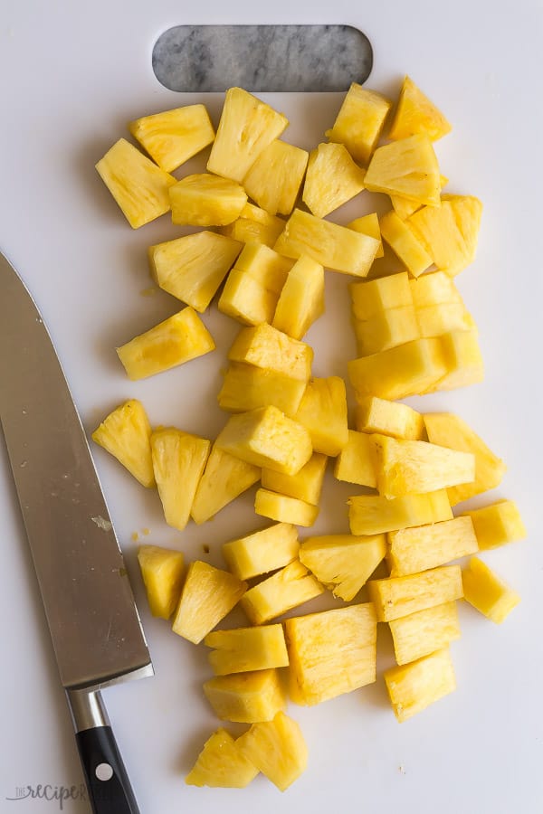 pineapple chunks on a white cutting board with knife