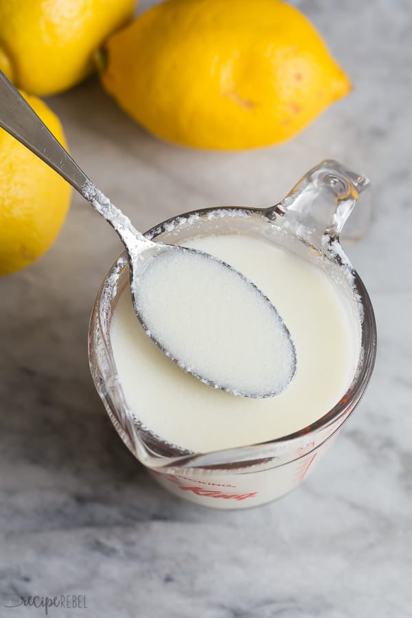 homemade buttermilk recipe in glass measuring cup with metal spoon scooping some milk