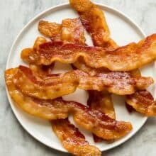 crispy oven baked bacon on white plate on grey marble background overhead