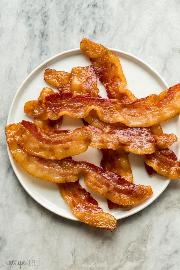 crispy oven baked bacon on white plate on grey marble background overhead