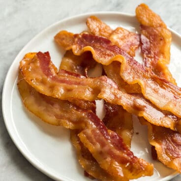 crispy oven bacon on white plate on grey marble background