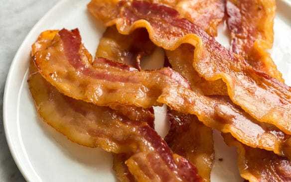 crispy oven bacon on white plate on grey marble background