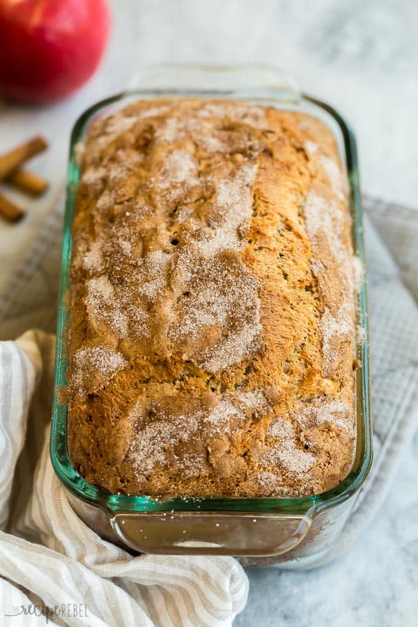 This Apple Bread is made with warm cinnamon, tender chunks of apple, applesauce, greek yogurt and whole wheat flour for a healthier twist that tastes indulgent! #bread #apple #recipe #baking #breakfast apple bread in glass loaf pan with cinnamon sugar on top