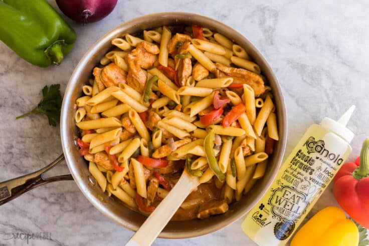 chicken fajita pasta in skillet with peppers and canola oil bottle on the side