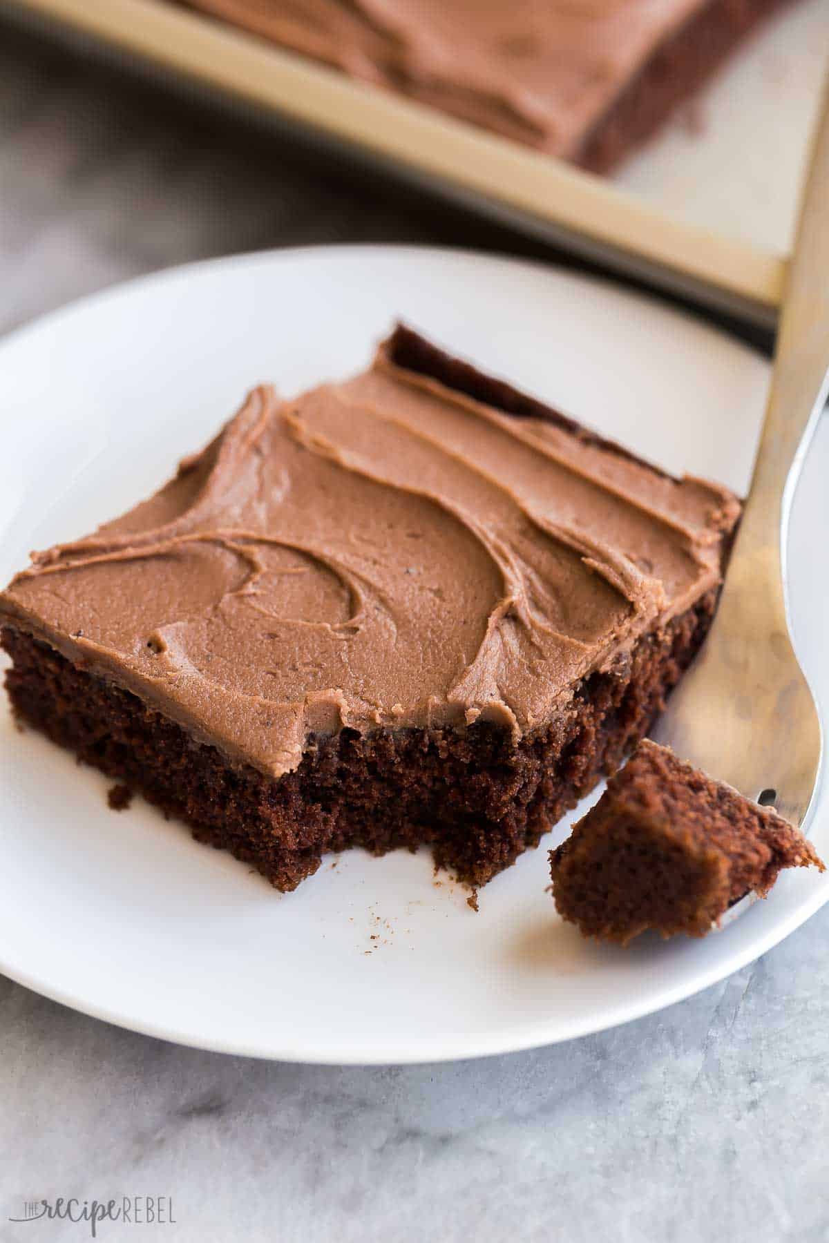 This Chocolate Sheet Cake is rich and chocolatey and so easy to make! Topped with a simple frosting made of melted butter, cocoa and sugar. It's sure to be a hit at any potluck! #chocolate #dessert #recipe | chocolate desserts | chocolate recipes | easy cake recipe | potluck dessert | holiday dessert | easy chocolate cake | easy dessert recipes one piece of chocolate sheet cake on a white plate.