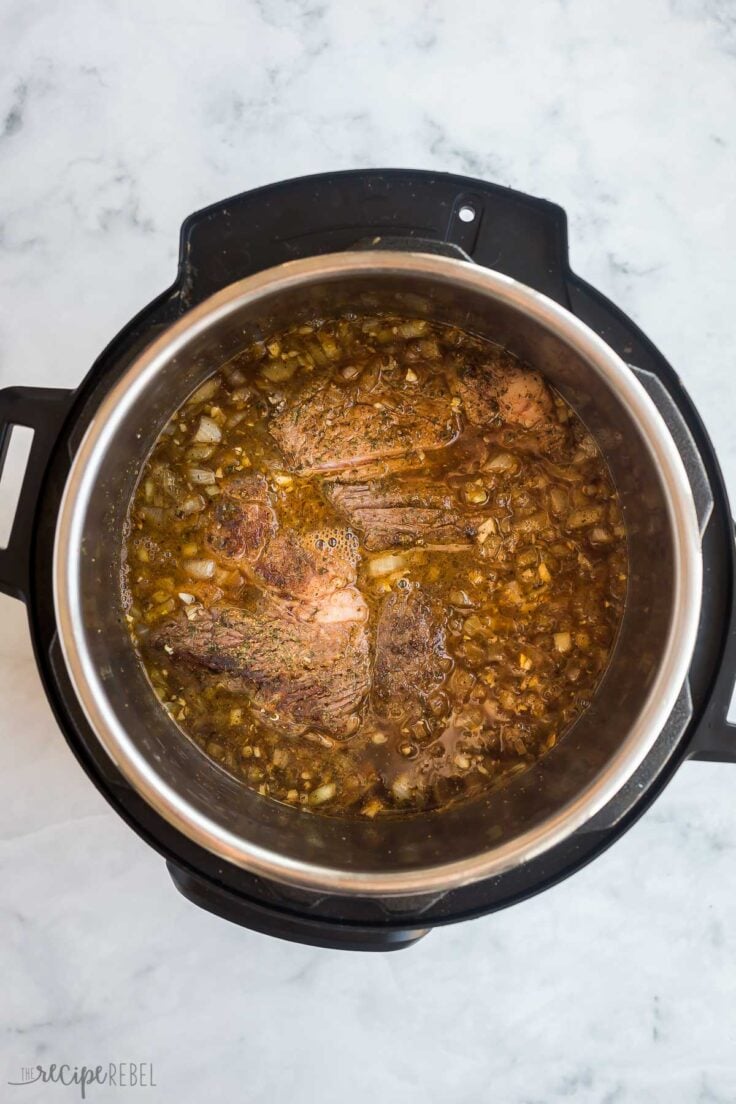 seared beef in instant pot with broth ready to pressure cook