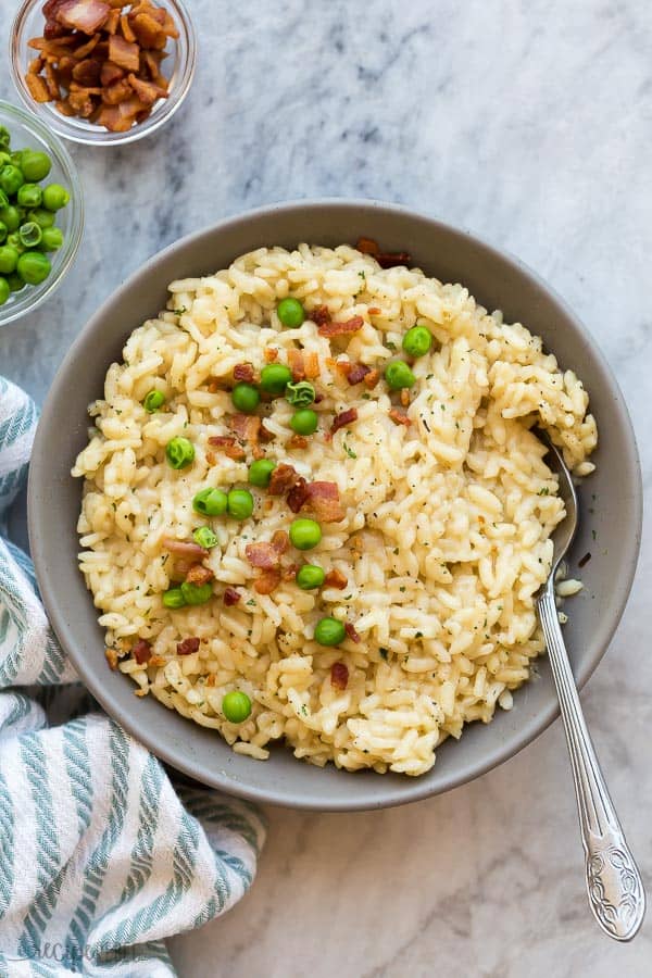 instant pot risotto in grey bowl with green peas and crispy bacon