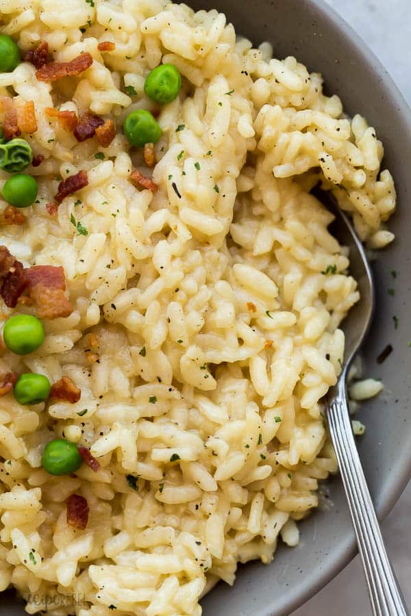 close up image of risotto in grey bowl with bacon and peas
