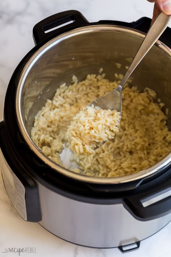 This Easy Instant Pot Risotto has the same creamy texture and perfectly al dente rice as the stove top version, but with much less effort! #risotto #sidedish #instantpot #pressurecooker scooping risotto out of instant pot with metal spoon