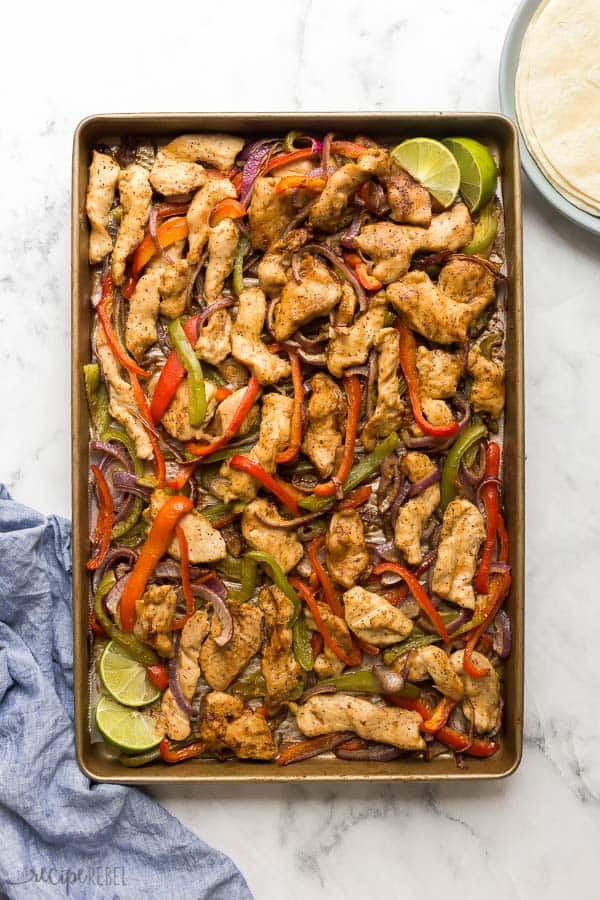 These Sheet Pan Chicken Fajitas are an easy dinner idea, ready in 30 minutes with only one dirty pan! #chicken #chickenrecipe #dinner #chickendinner #recipes overhead image of a sheet pan with cooked chicken strips bell peppers and onions