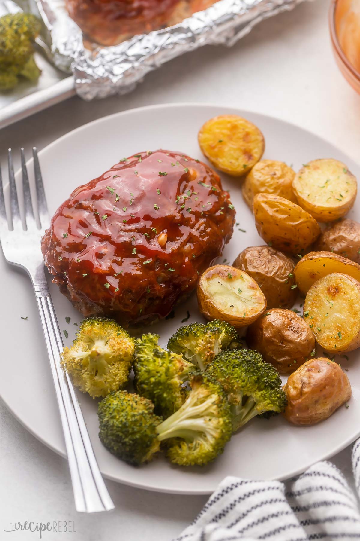 grey plate with mini meatloaf, potatoes and broccoli.