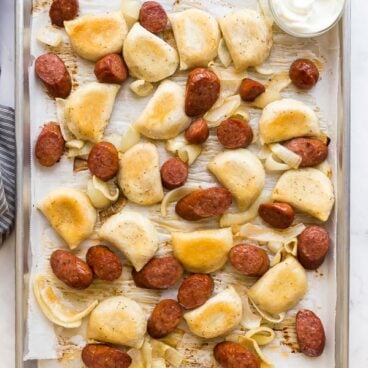 sheet pan sausage and perogies on parchment lined baking sheet