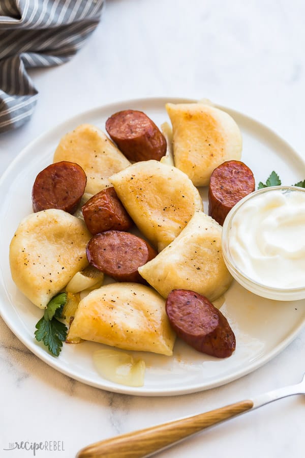 sausage slices and perogies on white plate on white background