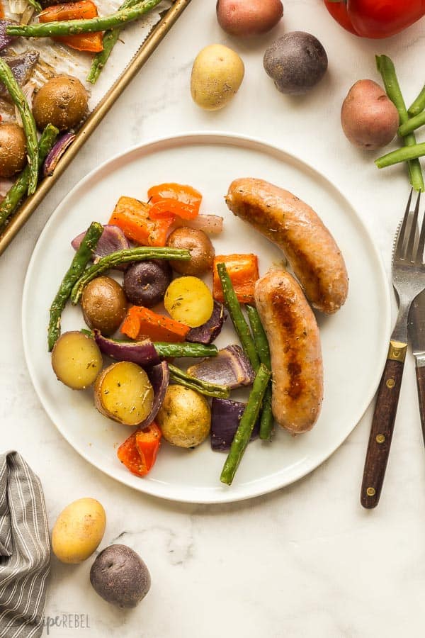 white plate with two sausages and potatoes red pepper and green beans