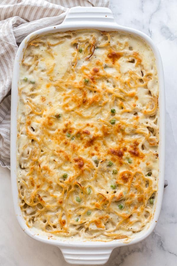 This Turkey Tetrazzini is a creamy baked pasta with a homemade sauce, shredded turkey, spaghetti and a golden cheesy crust! Make ahead and freezer friendly! #turkey #pasta #dinner #recipes overhead image of turkey tetrazzini in white baking dish