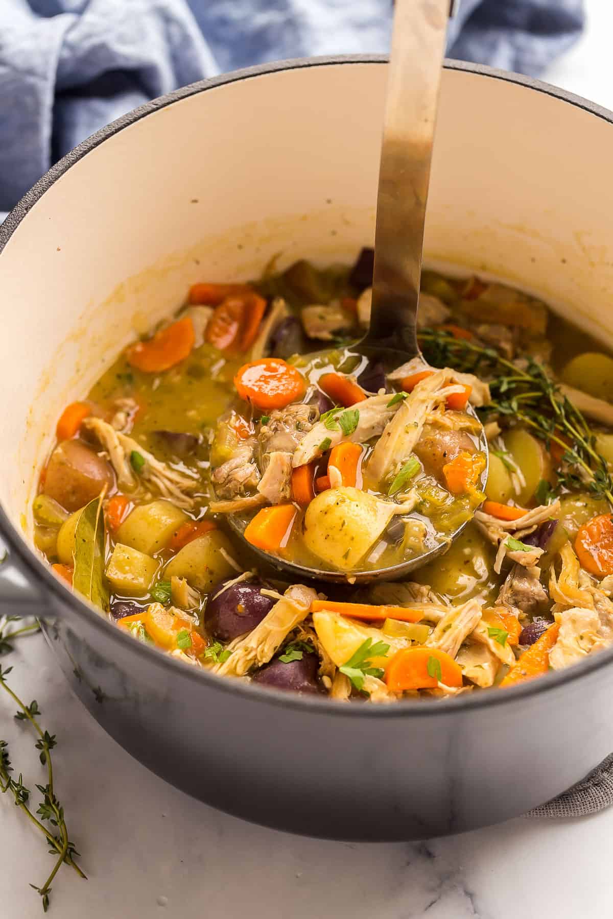 metal ladle scooping chicken stew from dutch oven.