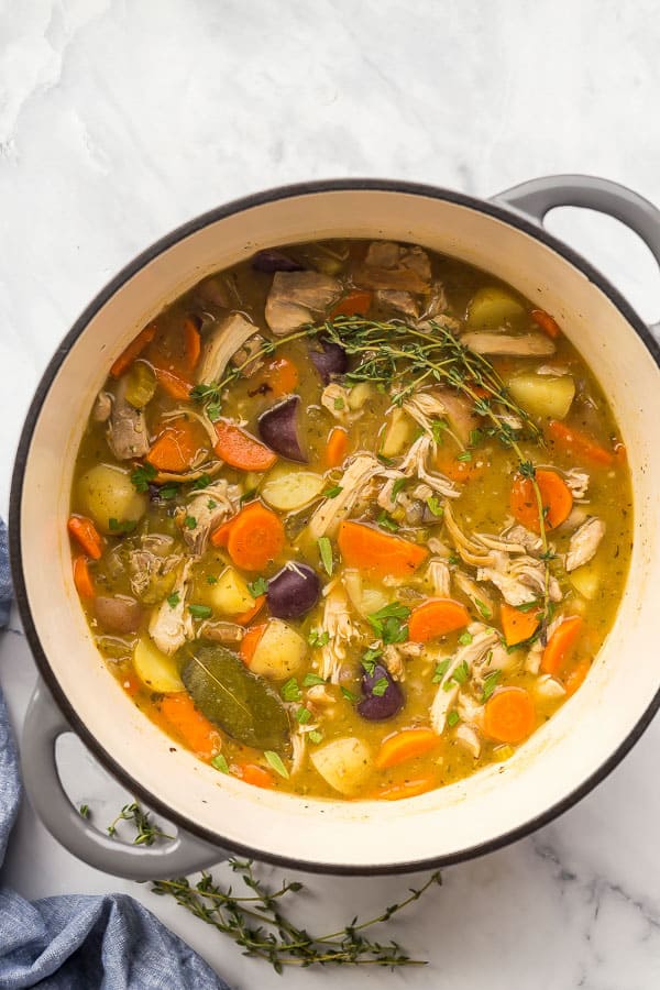 This easy and flavorful Chicken Stew is made in one pot with chicken thighs or breasts, potatoes, carrots, and onions with a rich and creamy sauce. It's the perfect comfort food for any time of year! #chicken #dinner #recipes #healthy overhead image of chicken stew in grey dutch oven