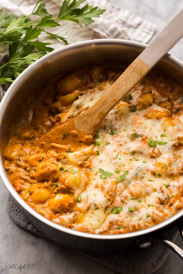 italian sausage gnocchi skillet with wooden spoon scooping