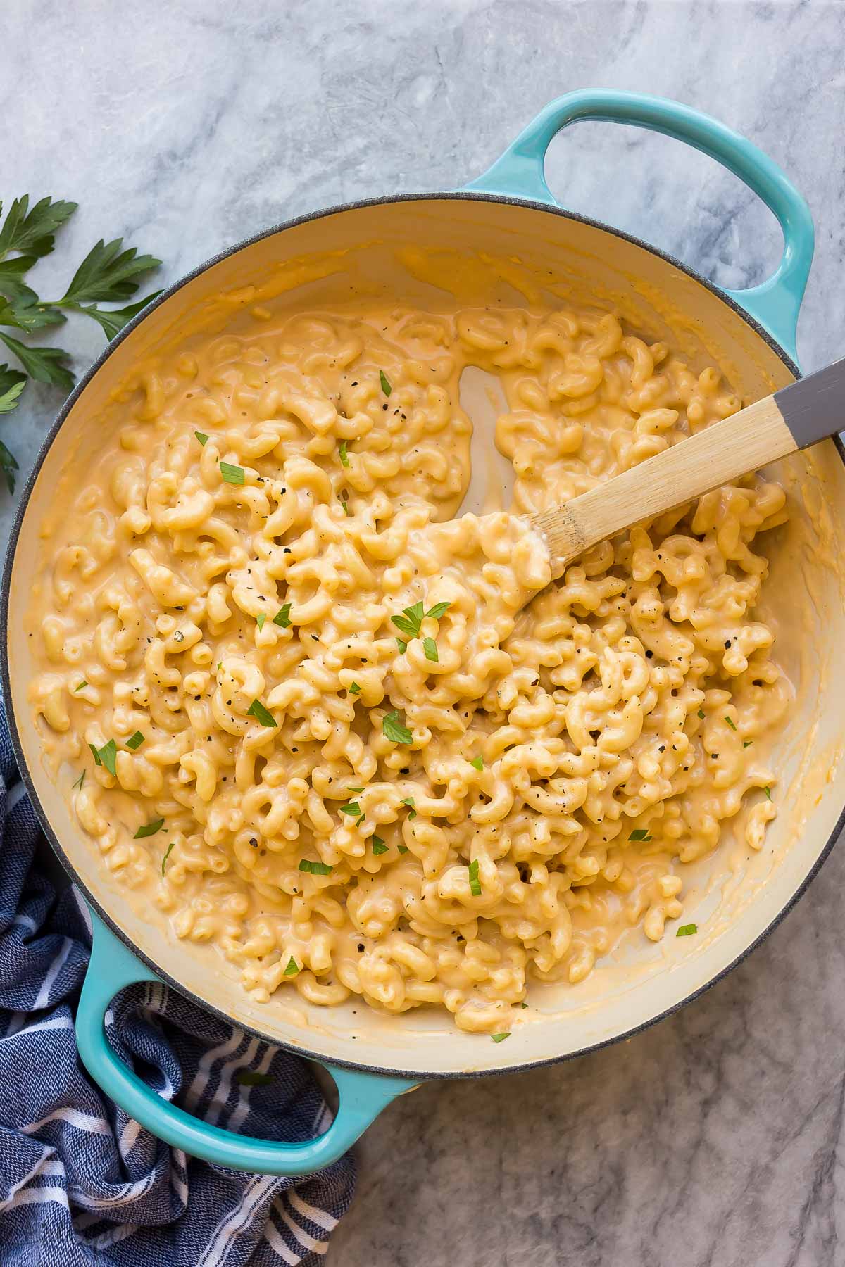 This Easy Mac and Cheese recipe is made in ONE pot with just SIX ingredients! Ready in 30 minutes or less, with full step by step video down in the recipe card. #macandcheese #pasta #macaroni #dinner #recipes blue skillet of mac and cheese on marble background with wooden spoon