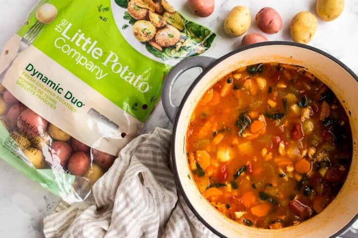 overhead image of chicken vegetable soup with bag of little potatoes