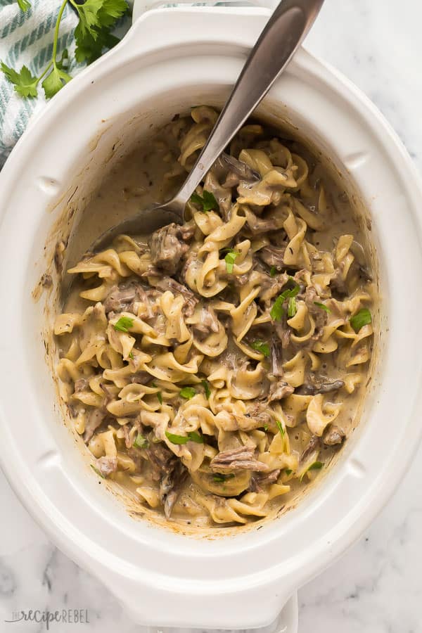 This Crock Pot Beef and Noodles is an easy 6 ingredient dinner that requires little prep time! Rich, creamy and comforting! Step by step recipe video down in the recipe card. #crockpot #slowcooker #beef #dinner overhead image of crockpot beef and noodles in slow cooker