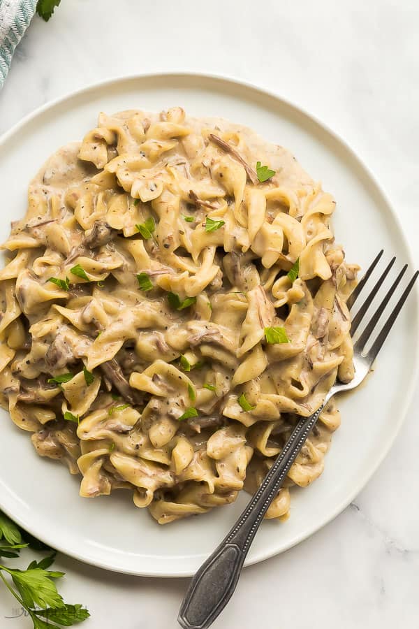 creamy beef and noodles on plate with fork stuck on the side