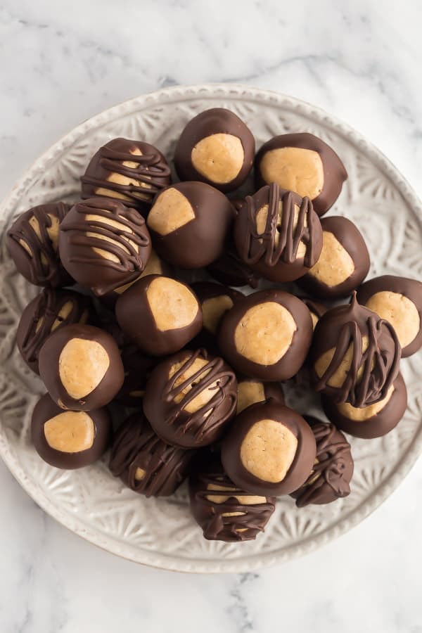 These Peanut Butter Balls are a no bake peanut butter truffle covered in chocolate! Made with just a few ingredients, buckeyes are the perfect make ahead treat for the holidays #peanutbutter #christmas #chocolate #baking #dessert overhead image of peanut butter balls coated in chocolate