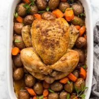 overhead image of roast chicken and vegetables in white baking dish