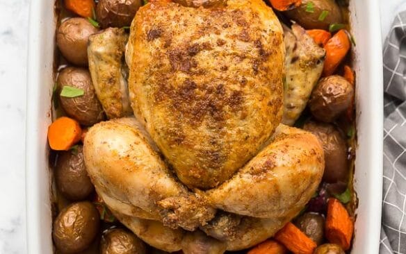 overhead image of roast chicken and vegetables in white baking dish