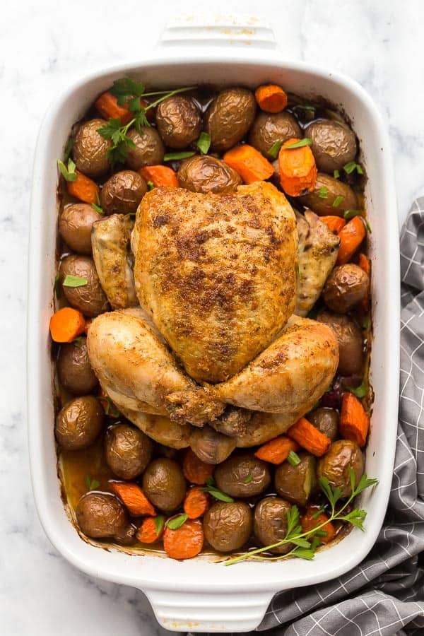 overhead image of roast chicken and vegetables in white baking dish