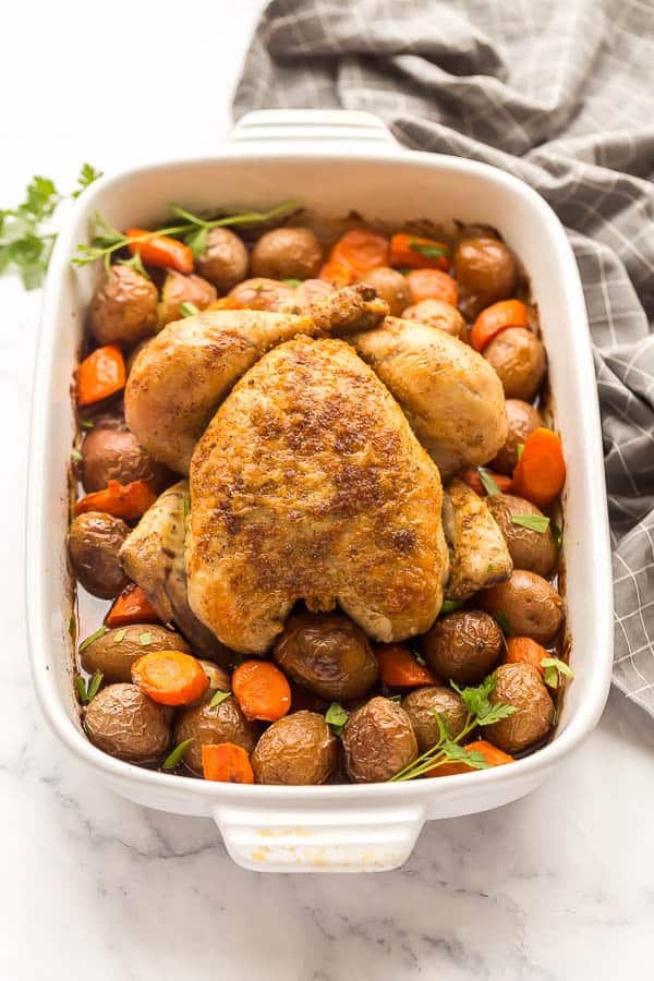 close up image of roast chicken with vegetables in white pan