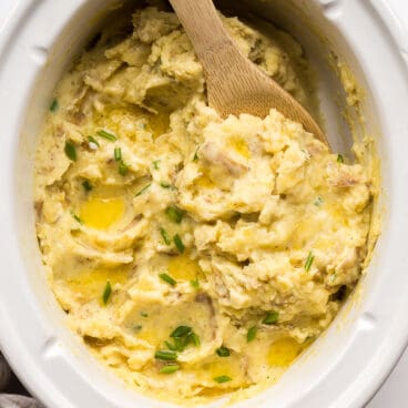 overhead image of slow cooker mashed potatoes with wooden spoon