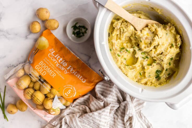 crockpot mashed potatoes in slow cooker with bag of Little Potatoes