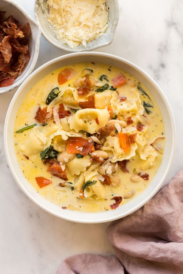 overhead image of bowl of spinach tortellini soup with crispy prosciutto