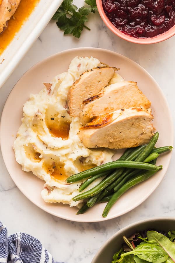 overhead image of turkey breast on plate with mashed potatoes and green beans