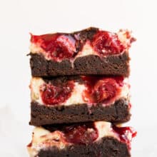 stack of three cherry cheesecake brownies on white background