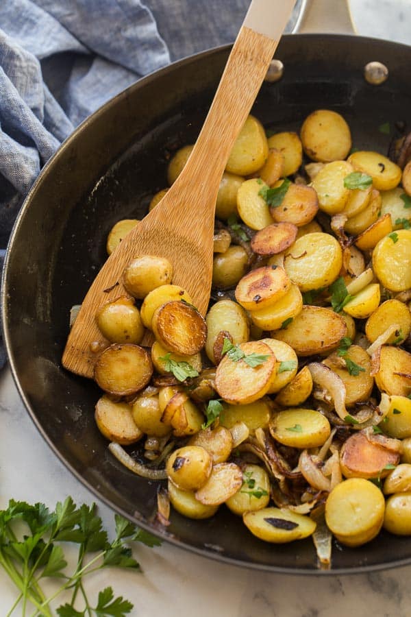 close up image of lyonnaise potatoes on wooden spoon