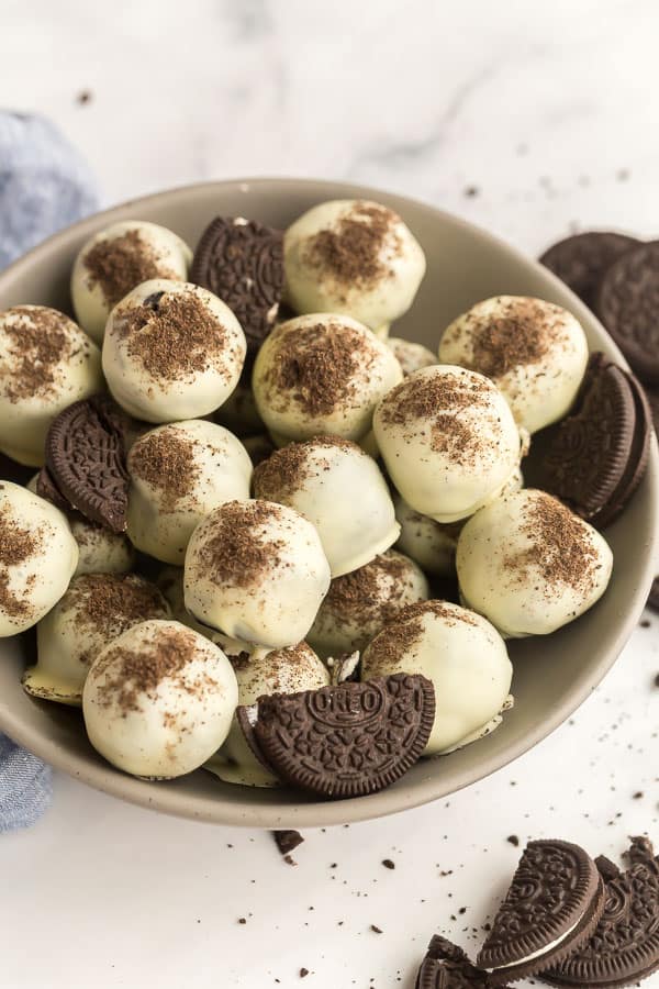These Oreo Balls are an easy, no bake dessert made with crushed Oreos and cream cheese. They come together easily in the food processor and are coated in melted chocolate! #oreo #christmas #candy #chocolate #recipe Oreo balls stacked in grey bowl