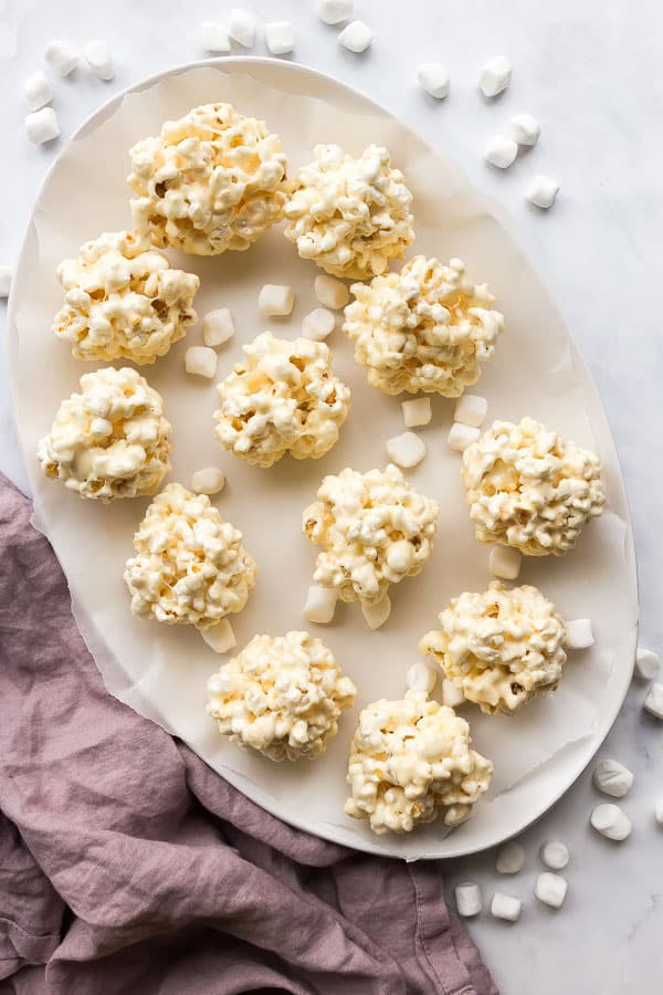 These Popcorn Balls are a fun holiday treat that the kids love! Experiment with flavors and colors to create something special for any occasion. #popcorn #christmas #holidays #recipes overhead image of popcorn balls on white platter
